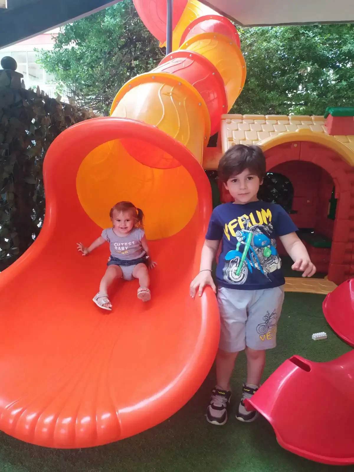 Kinder spielen auf einem Spielplatz mit einer Rutsche.