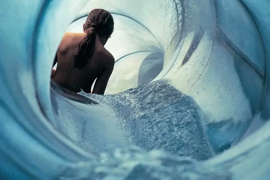 Eine Person rutscht in einem Wasserpark durch eine blaue Röhre.