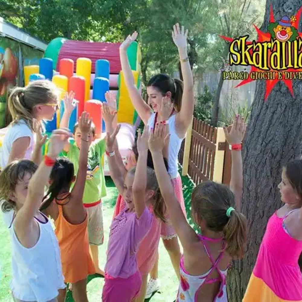alt="Kinder spielen und tanzen fröhlich im Freien unter der Anleitung von Betreuern." title="Kinder beim Spielen und Tanzen im Freien mit Betreuern."