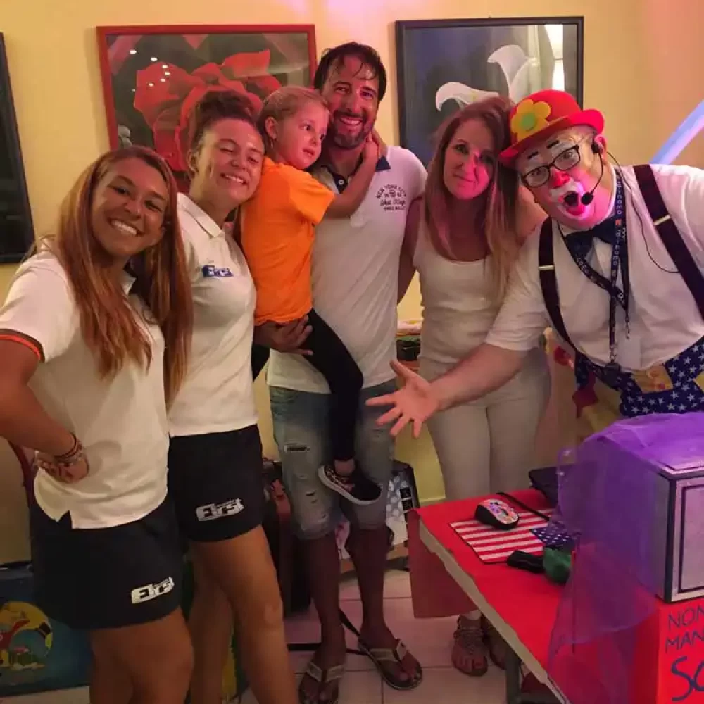 Eine Gruppe von Menschen posiert fröhlich mit einem Clown bei einer Feier.