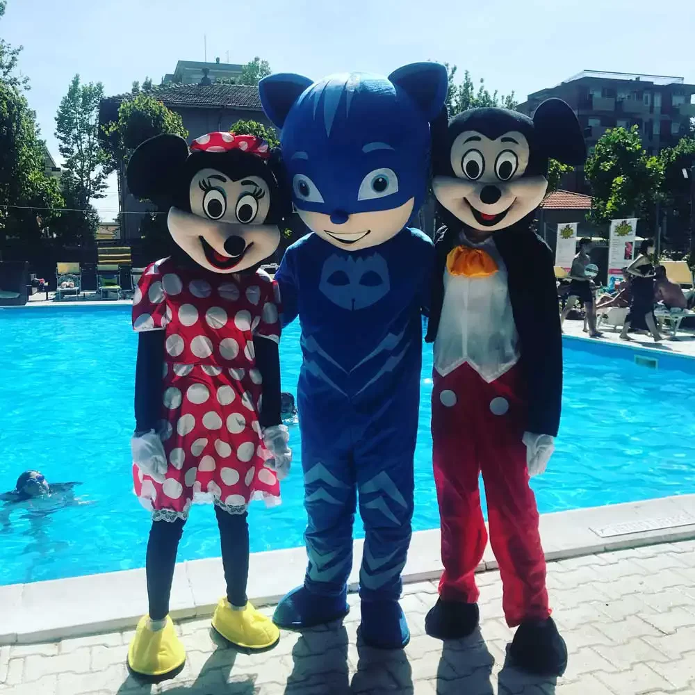 Drei Personen in Cartoon-Kostümen posieren lachend vor einem Pool.