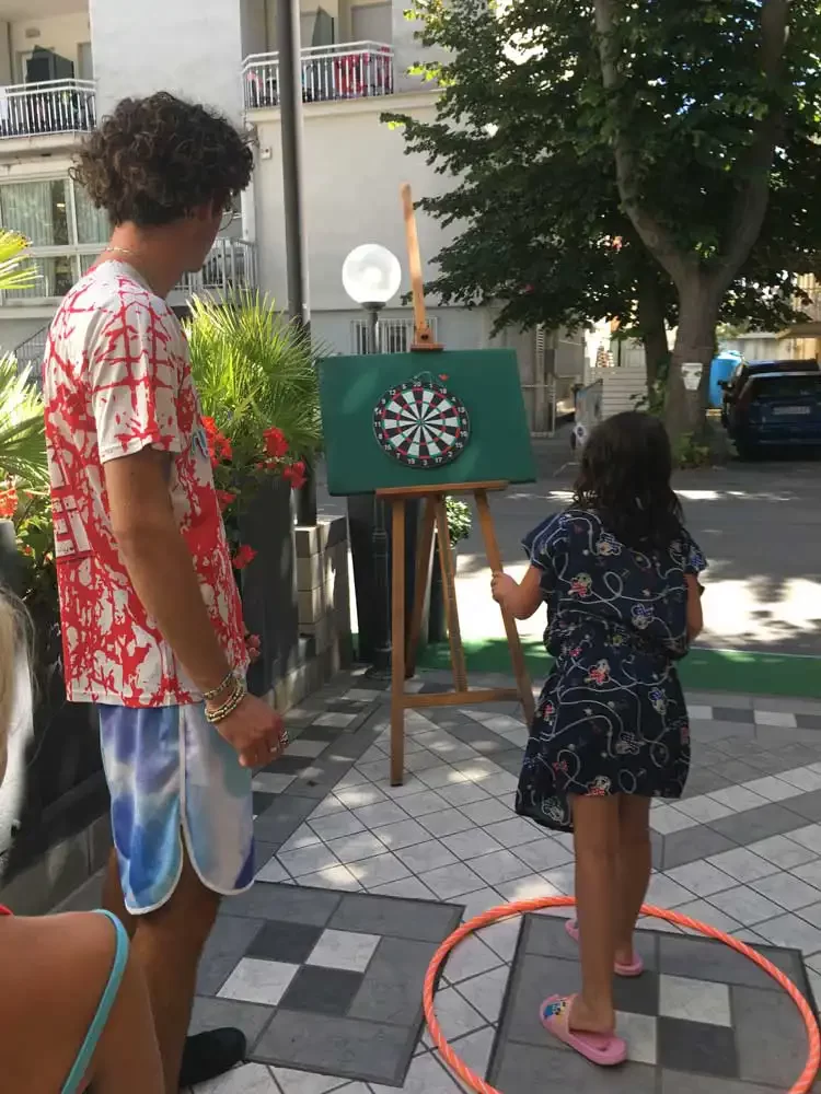 Eine Person beobachtet ein Kind, das auf eine Dartscheibe wirft.