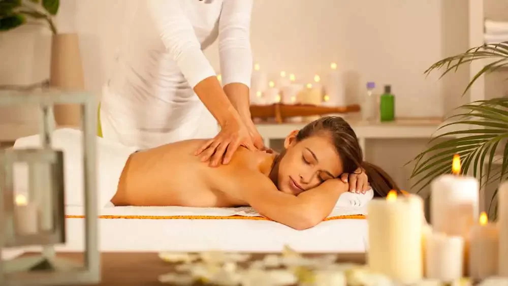Eine Person erhält eine Rückenmassage in entspannter, kerzenbeleuchteter Umgebung.